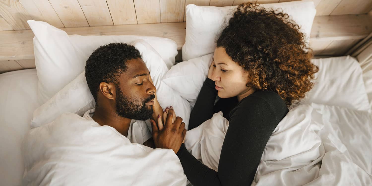 Couple sleeping peacefully in bed with white bedding, illustrating sleep cycles and sleep stages during a restful night.